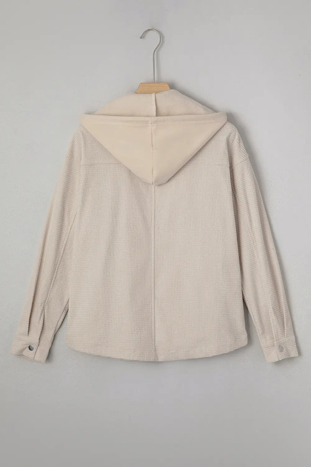 Beige jacket on a hanger against a plain background.