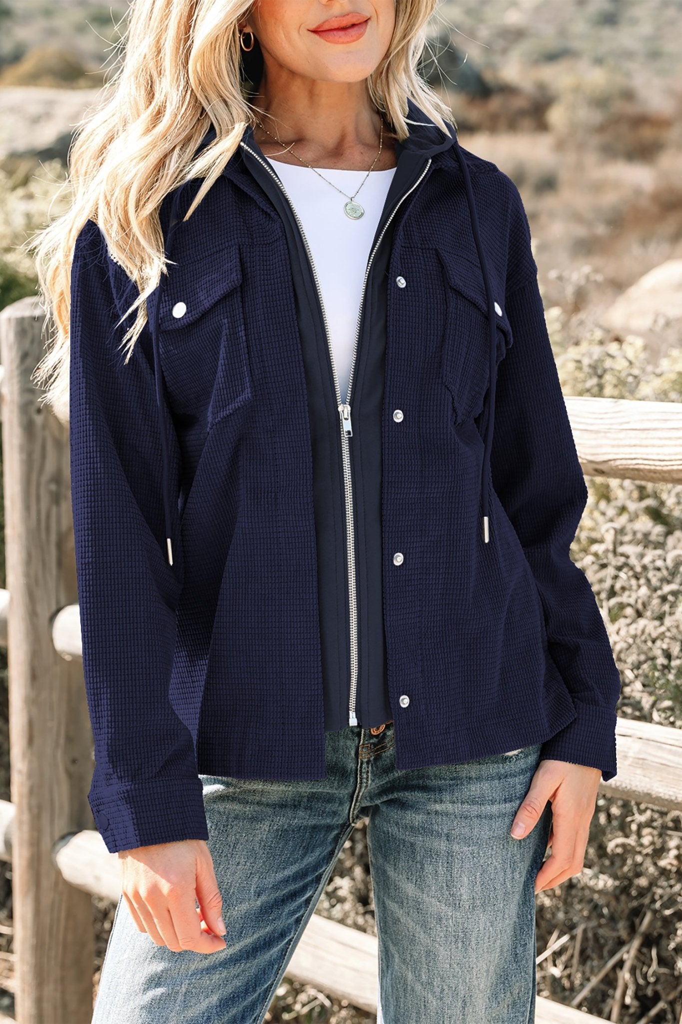 Woman wearing a navy blue jacket with white buttons, standing outdoors.