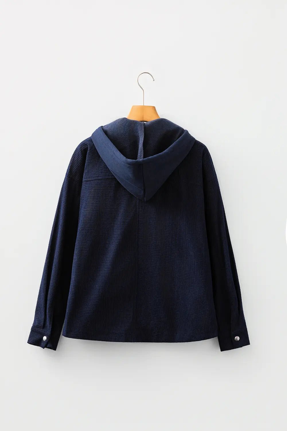 Dark navy hooded jacket with long sleeves and buttoned cuffs on a wooden hanger.