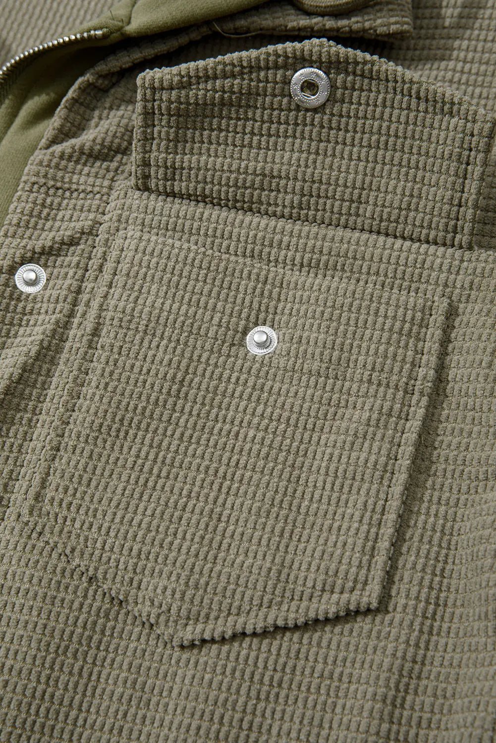 Close-up of an olive green waffle-knit jacket with chest pocket and silver snap buttons.