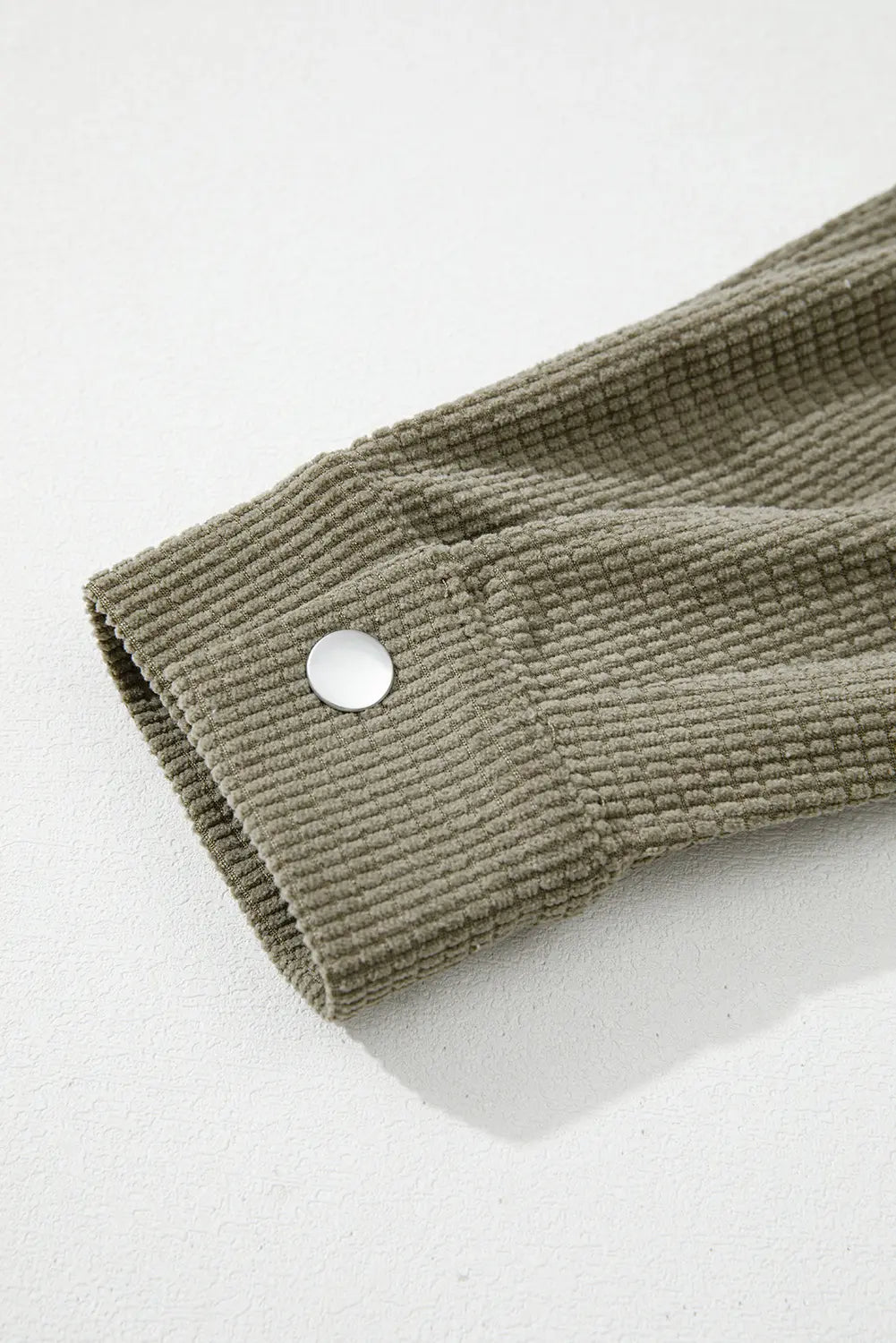 Close-up of a textured fabric with a button on a light background.