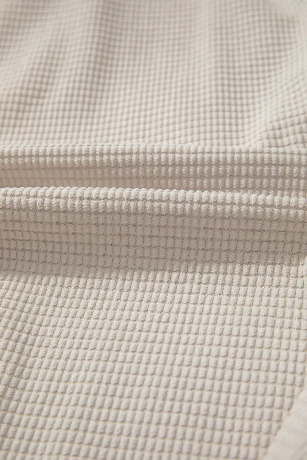 Close-up of beige textured fabric with a grid pattern.