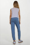 Woman wearing a light gray sleeveless top and blue pants on a white background