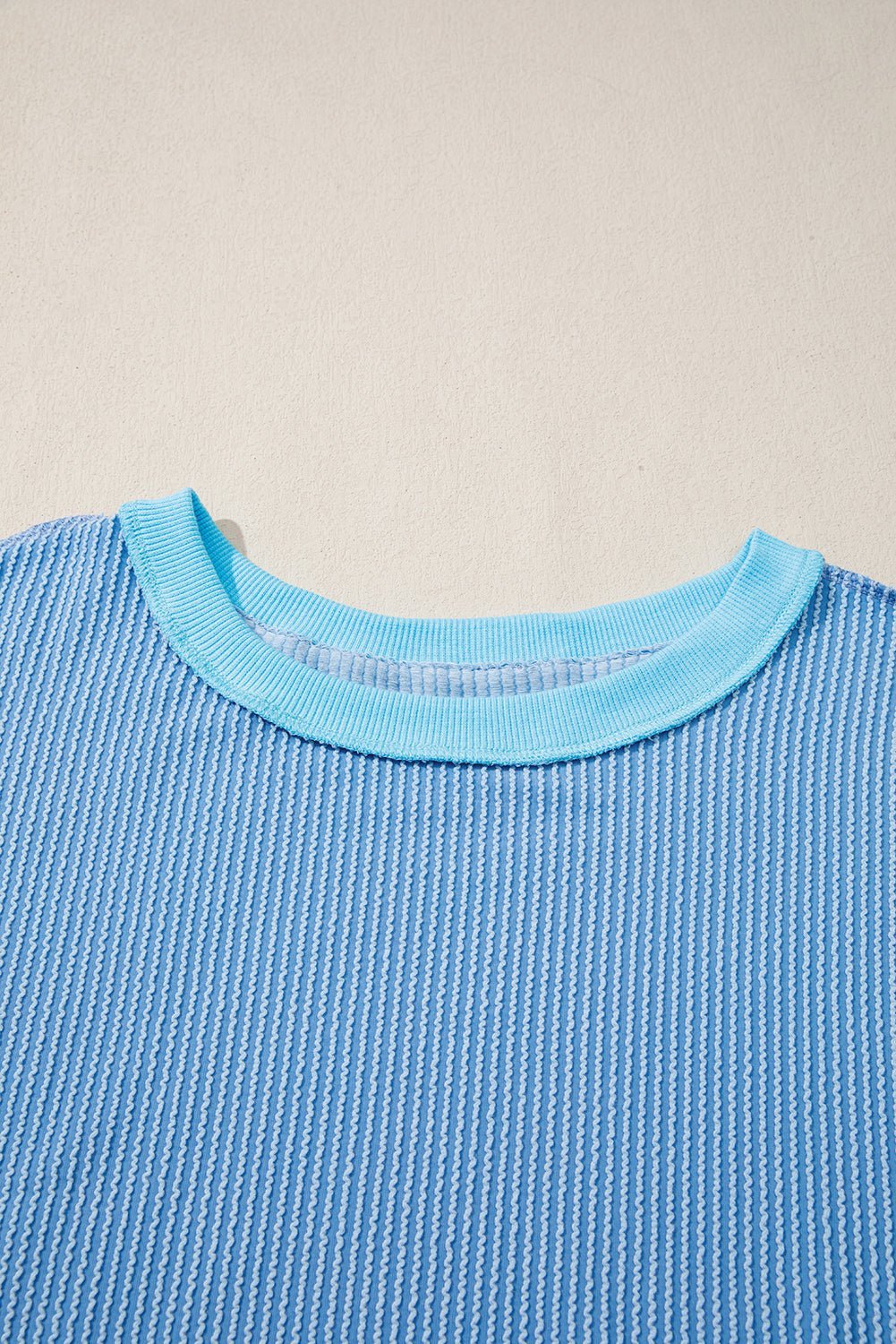 Close-up of a blue textured sweater with a beige background