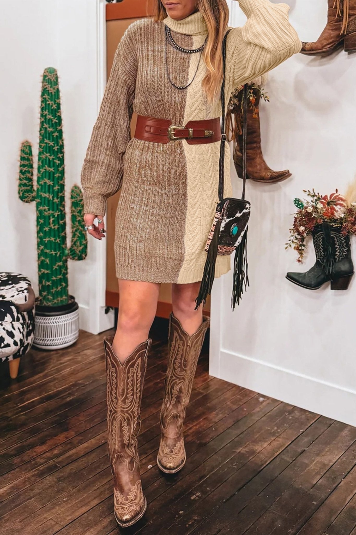 Woman in beige-cream knit midi dress with brown belt, fringe bag, and western boots.