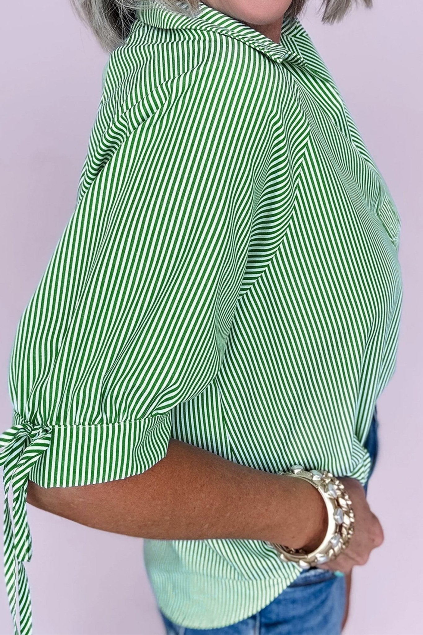 Green and white striped shirt worn by a person on a light purple background