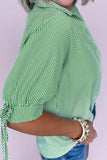 Green and white striped shirt worn by a person on a light purple background