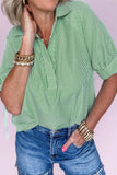 Person wearing a green striped shirt and blue jeans with gold bracelets on a light pink background
