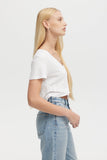 Woman wearing a white crop top and light blue jeans on a plain background