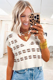 Woman taking a mirror selfie wearing a patterned top and denim shorts indoors.