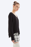 Woman wearing a black top and patterned pants on a white background
