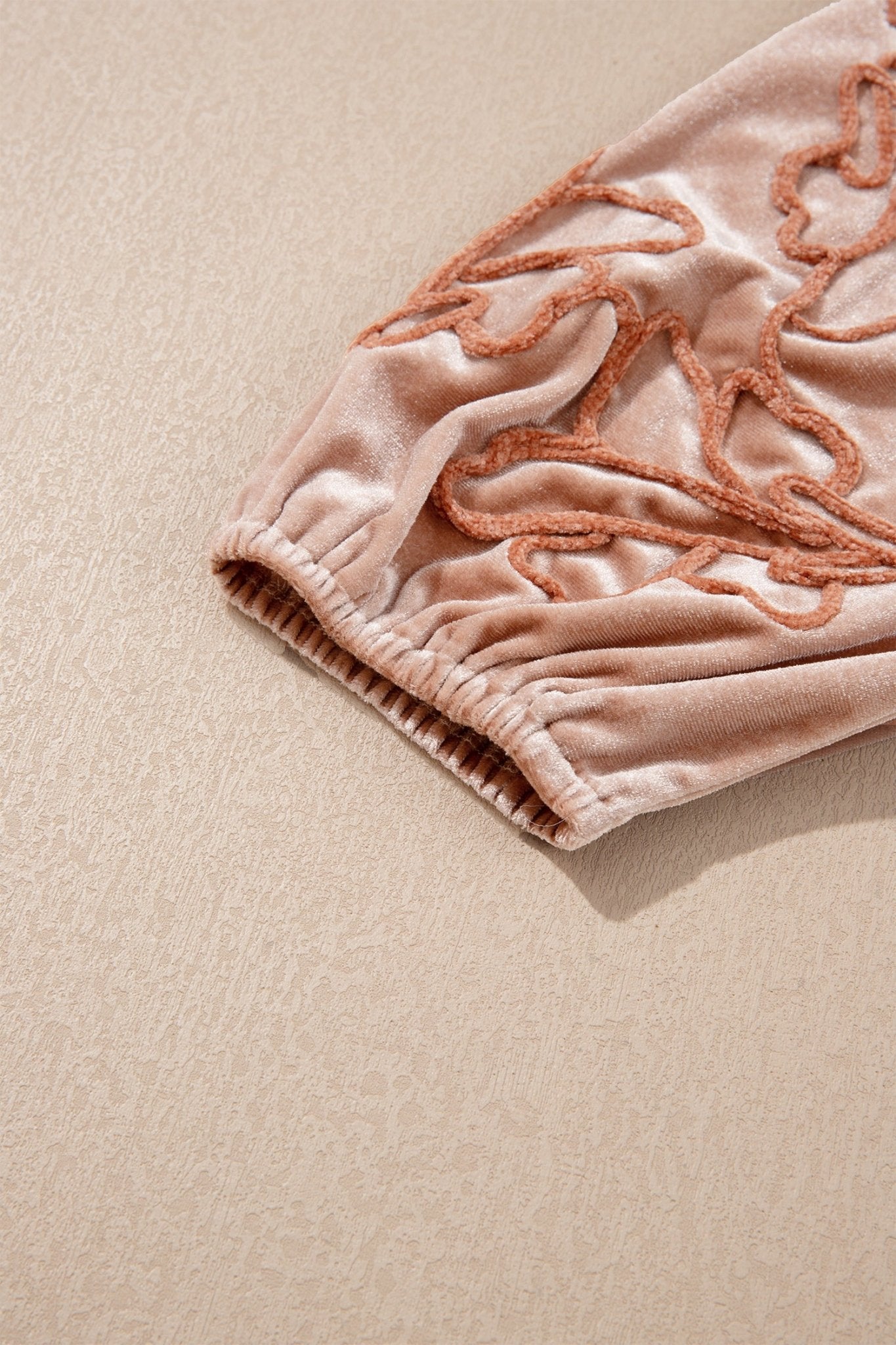 Close-up of dusty pink velvet with peach leaf embroidery and elastic cuff.