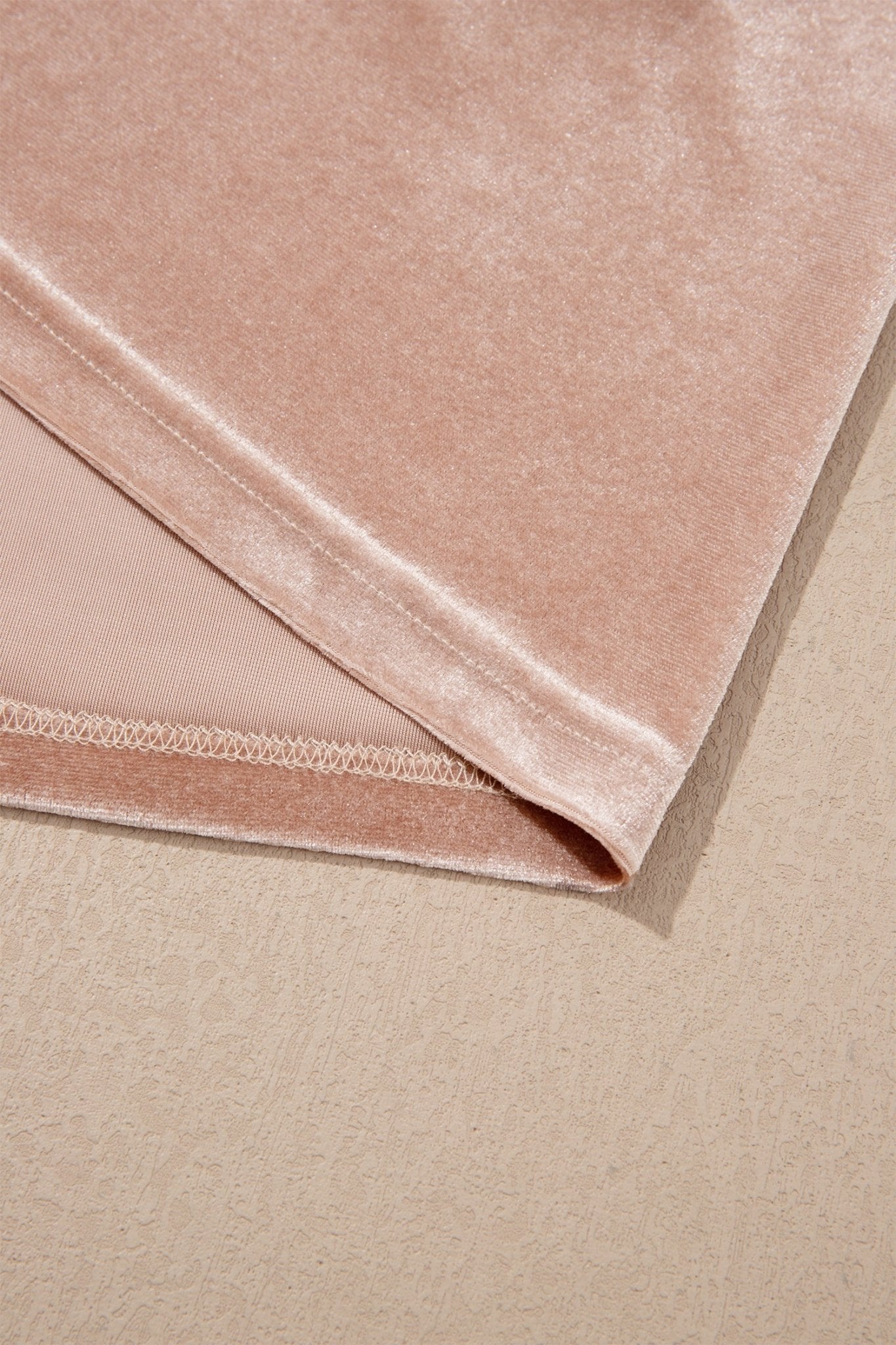 Close-up of folded dusty pink velvet showing soft texture and stitching.