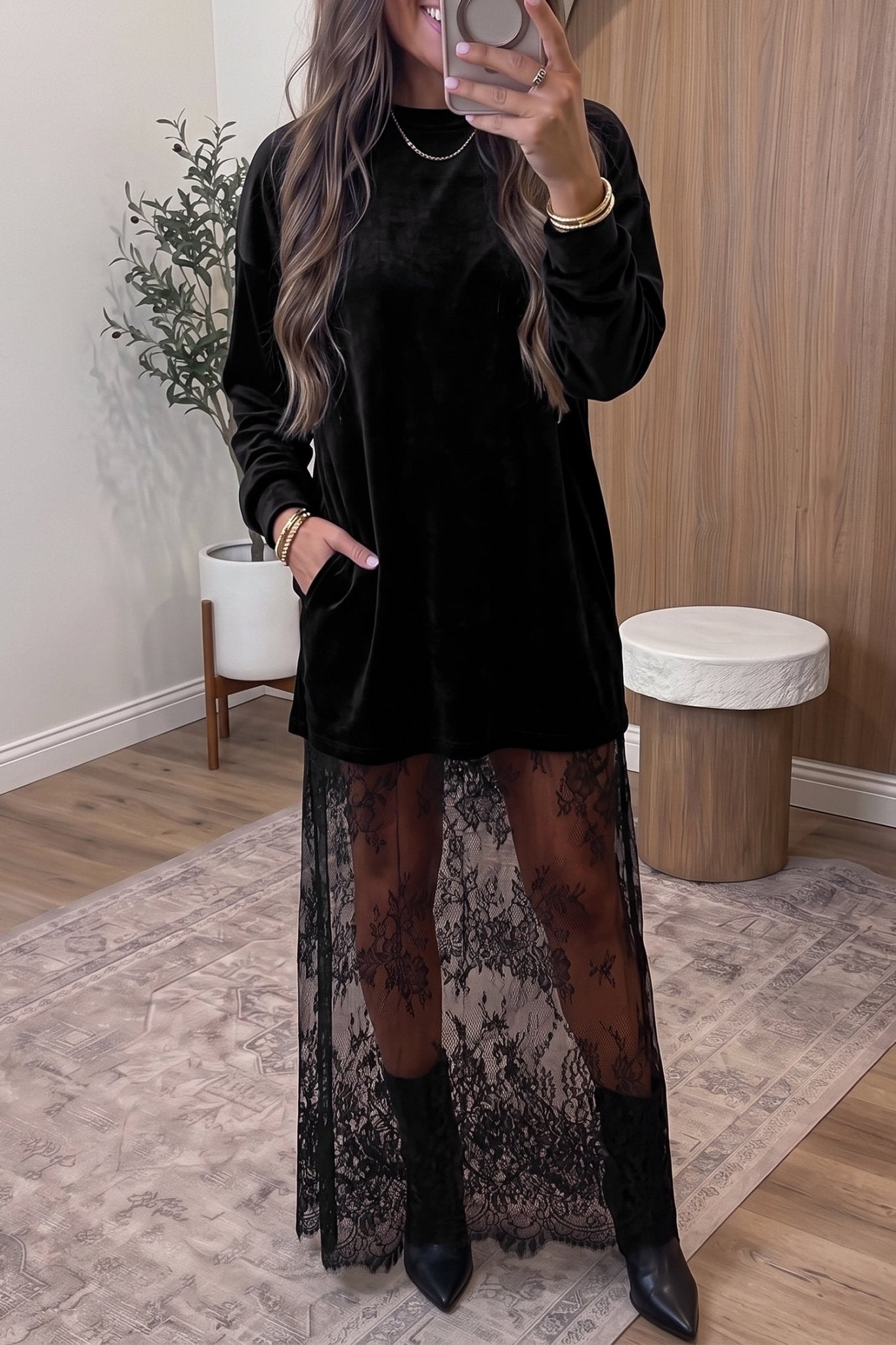 Woman in black velvet dress with sheer lace overlay, tights, and ankle boots.