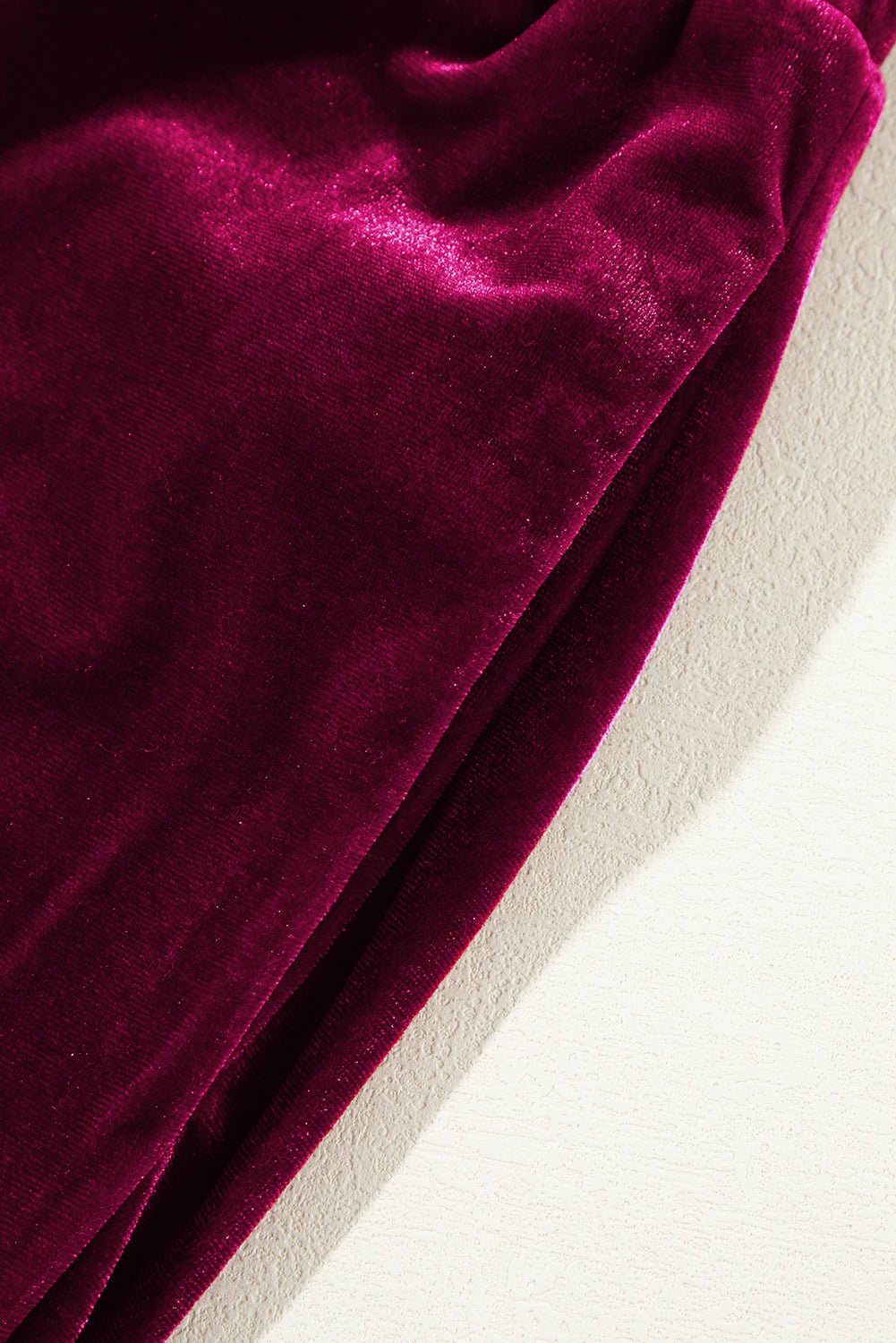 Close-up of deep red velvet fabric on a neutral background