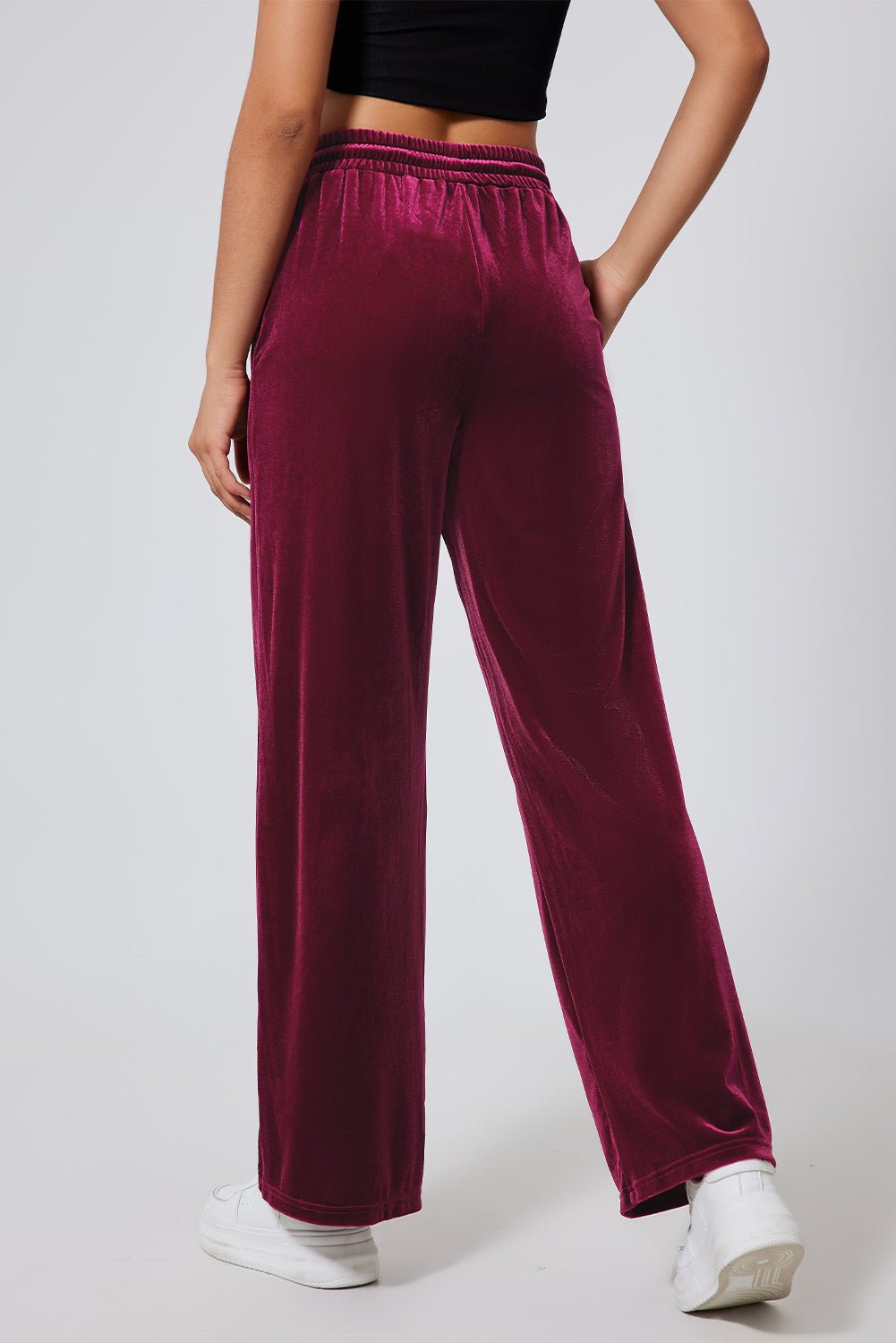 Person wearing burgundy velvet pants on a plain background