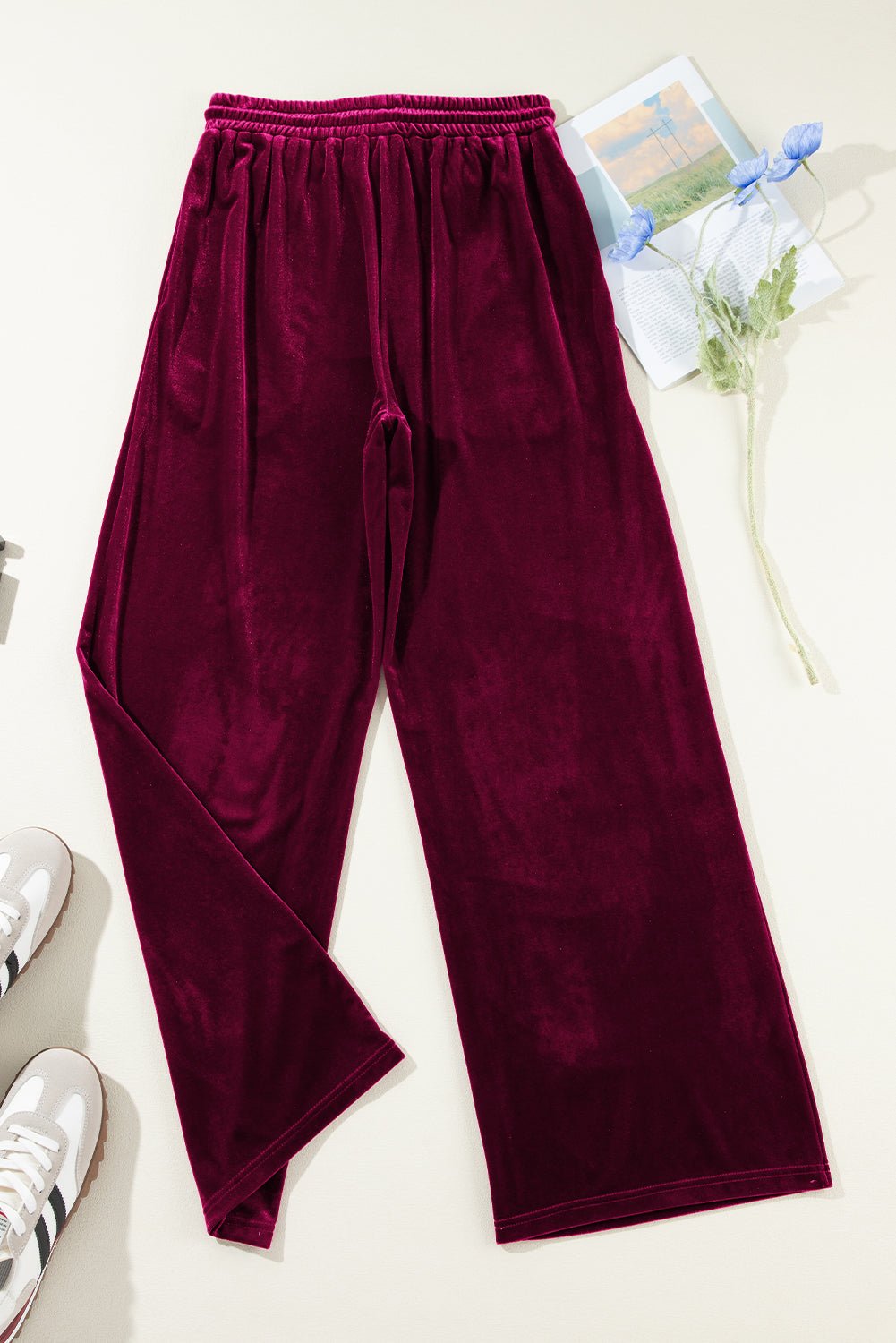 Maroon velour pants on a light surface with a blurred background