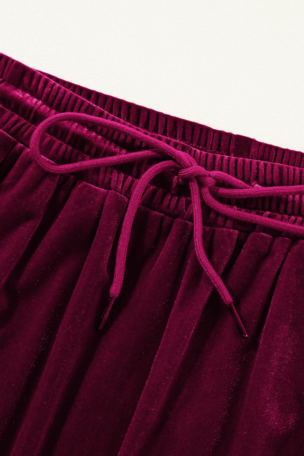 Close-up of a burgundy velvet skirt with drawstring waistband on a white background