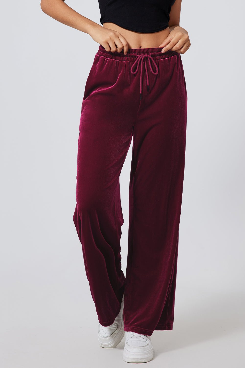 Maroon velvet pants worn by a person on a white background