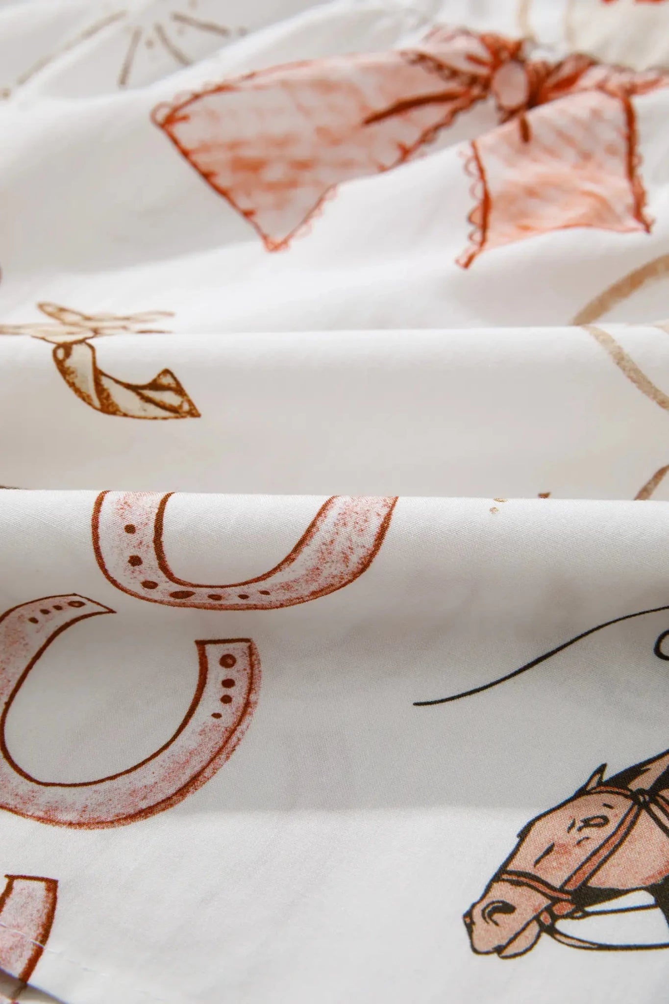Close-up of fabric with horse and horseshoe patterns on a white background