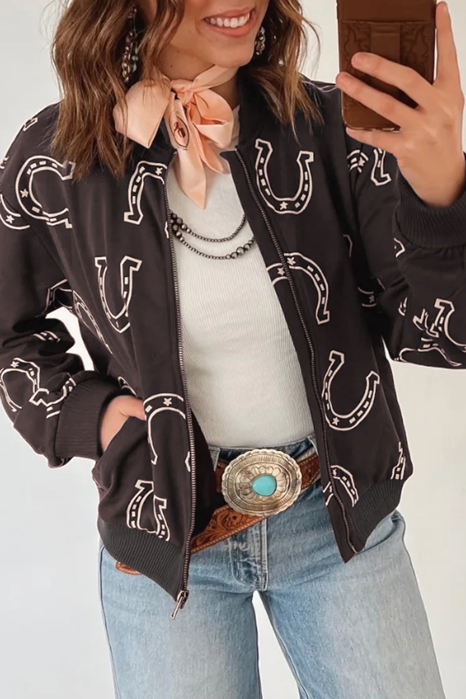 Brown horseshoe print zip up jacket with hand in side pocket, front view