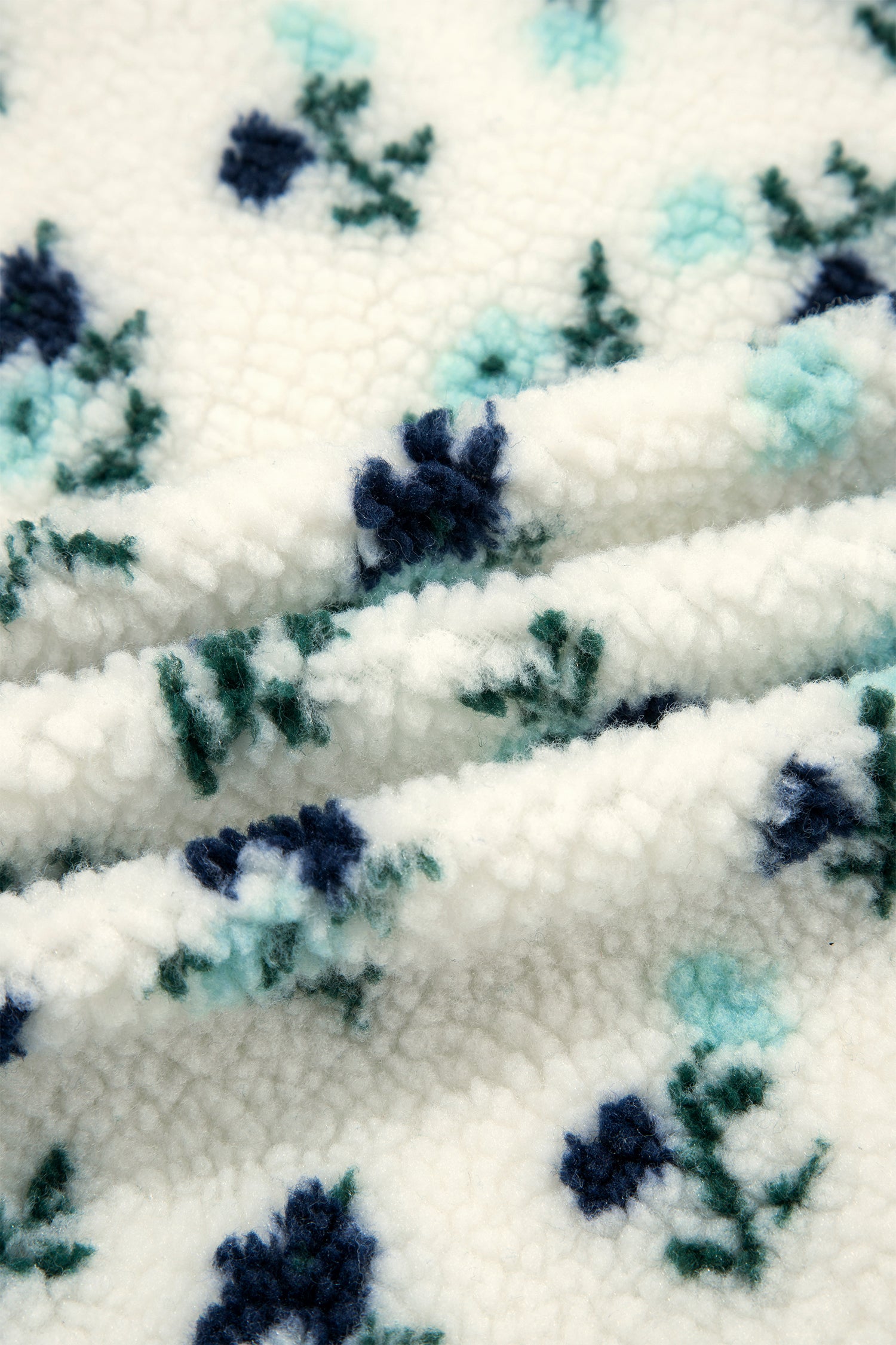 Close-up of fluffy white sherpa fabric with navy and teal floral print