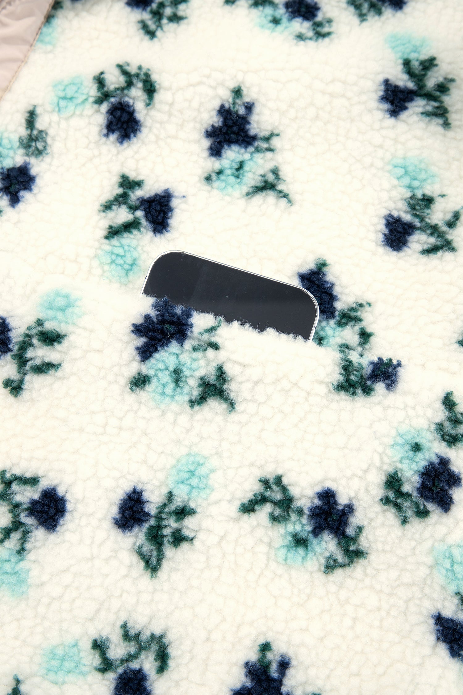 Side pocket holding a phone on white floral sherpa jacket