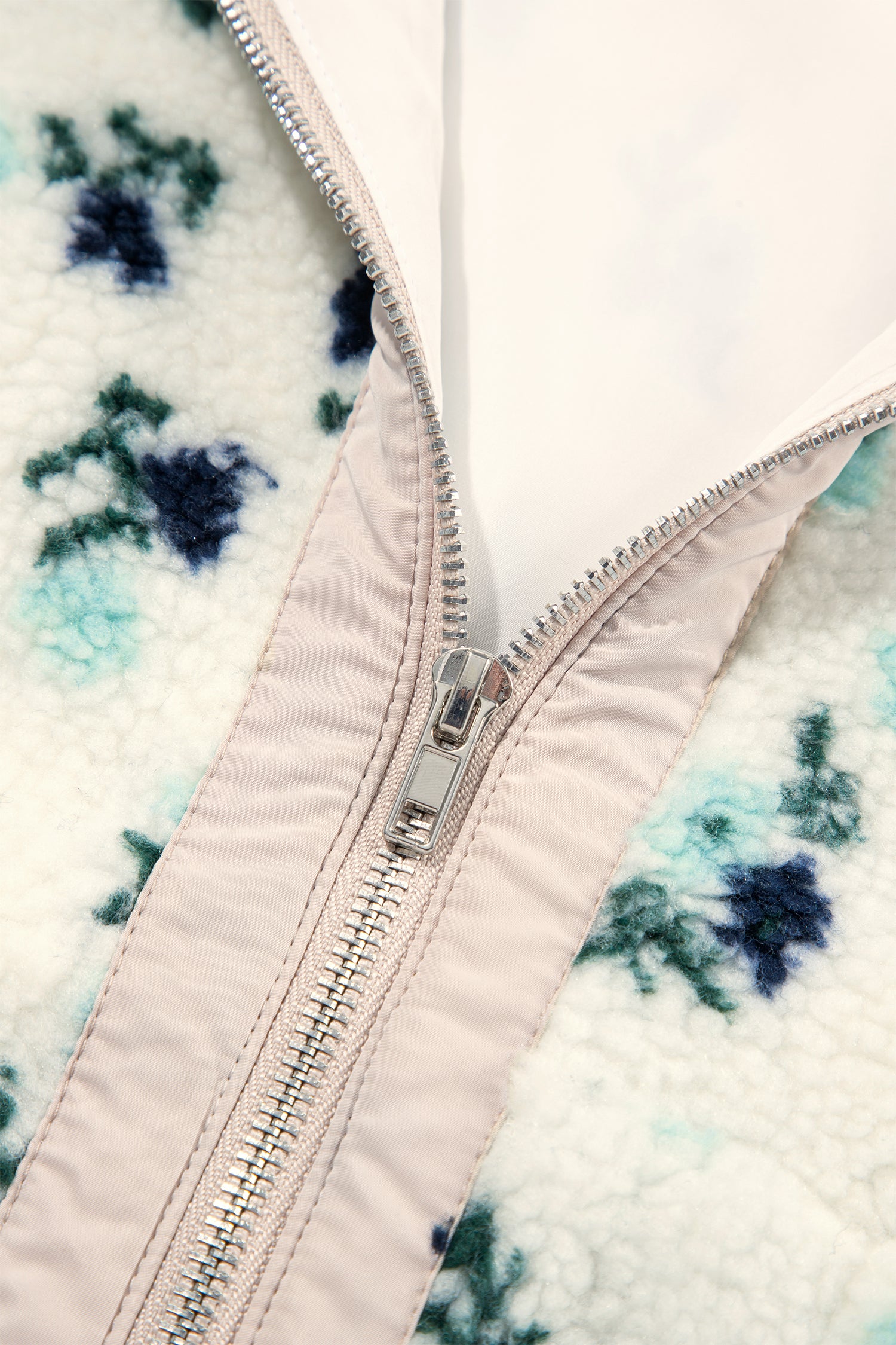 Metal zipper close-up on white floral sherpa jacket