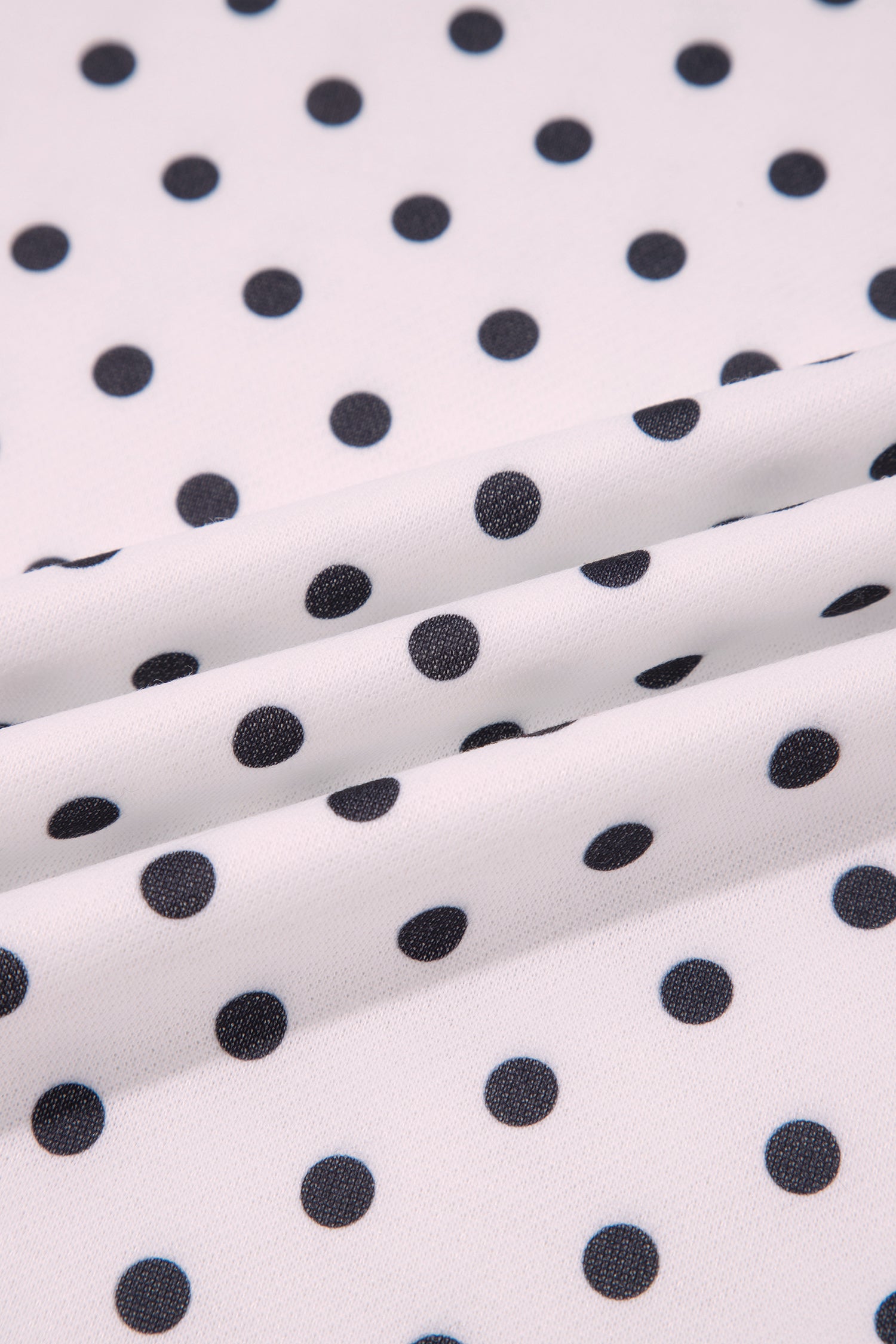Black polka dot print fabric close-up on white sweatshirt