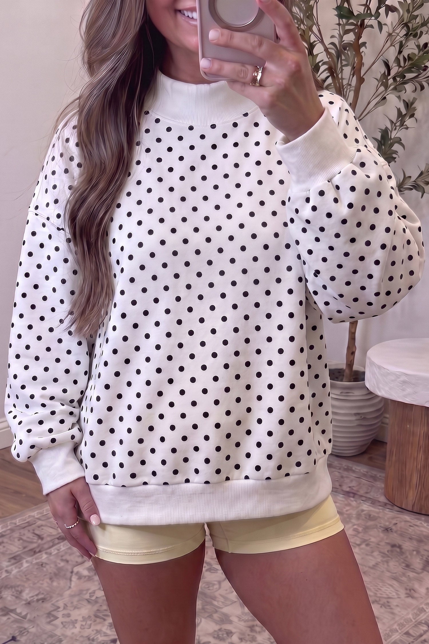 White polka dot mock neck sweatshirt with black dots, front view on model