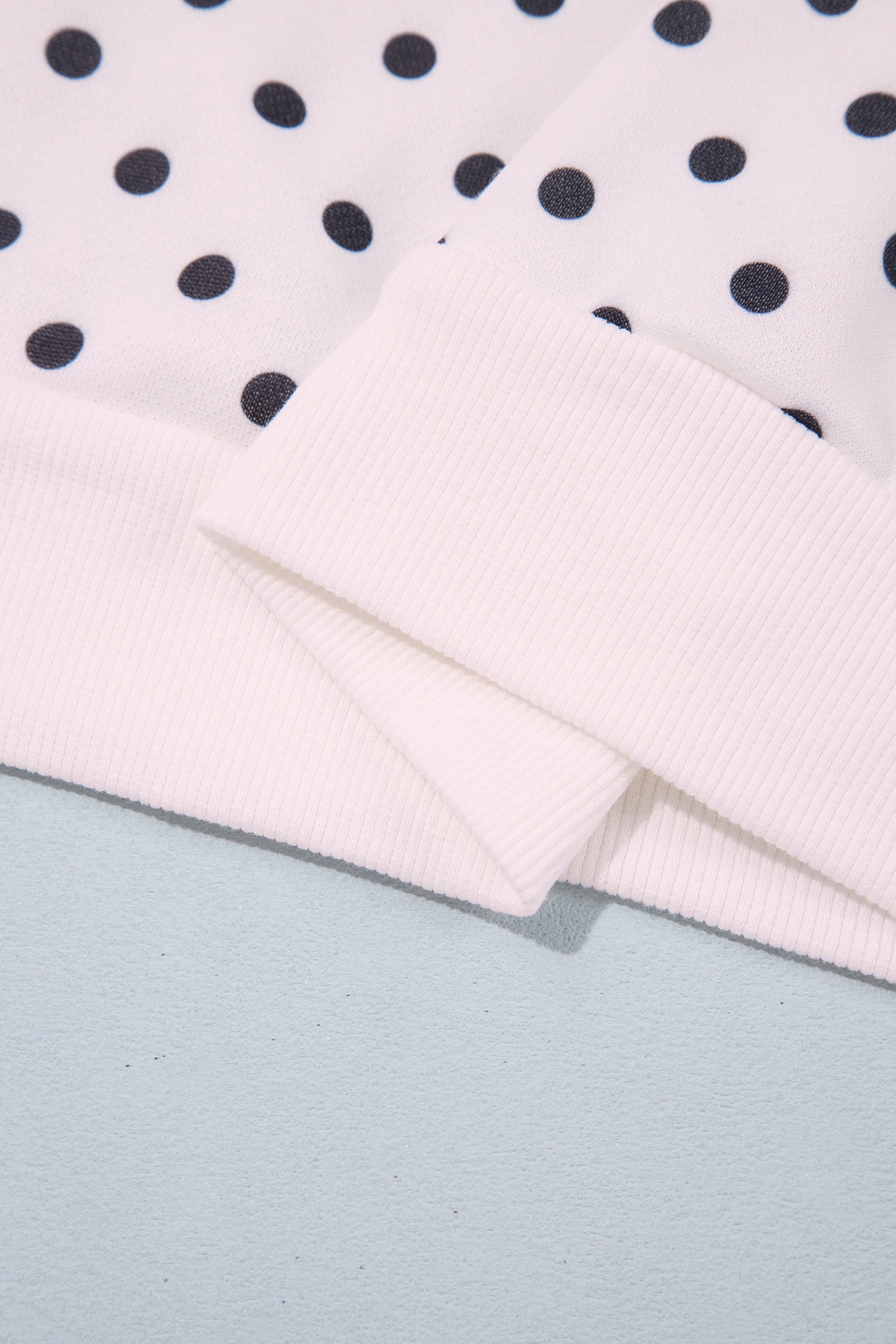 Banded hem detail on white polka dot sweatshirt