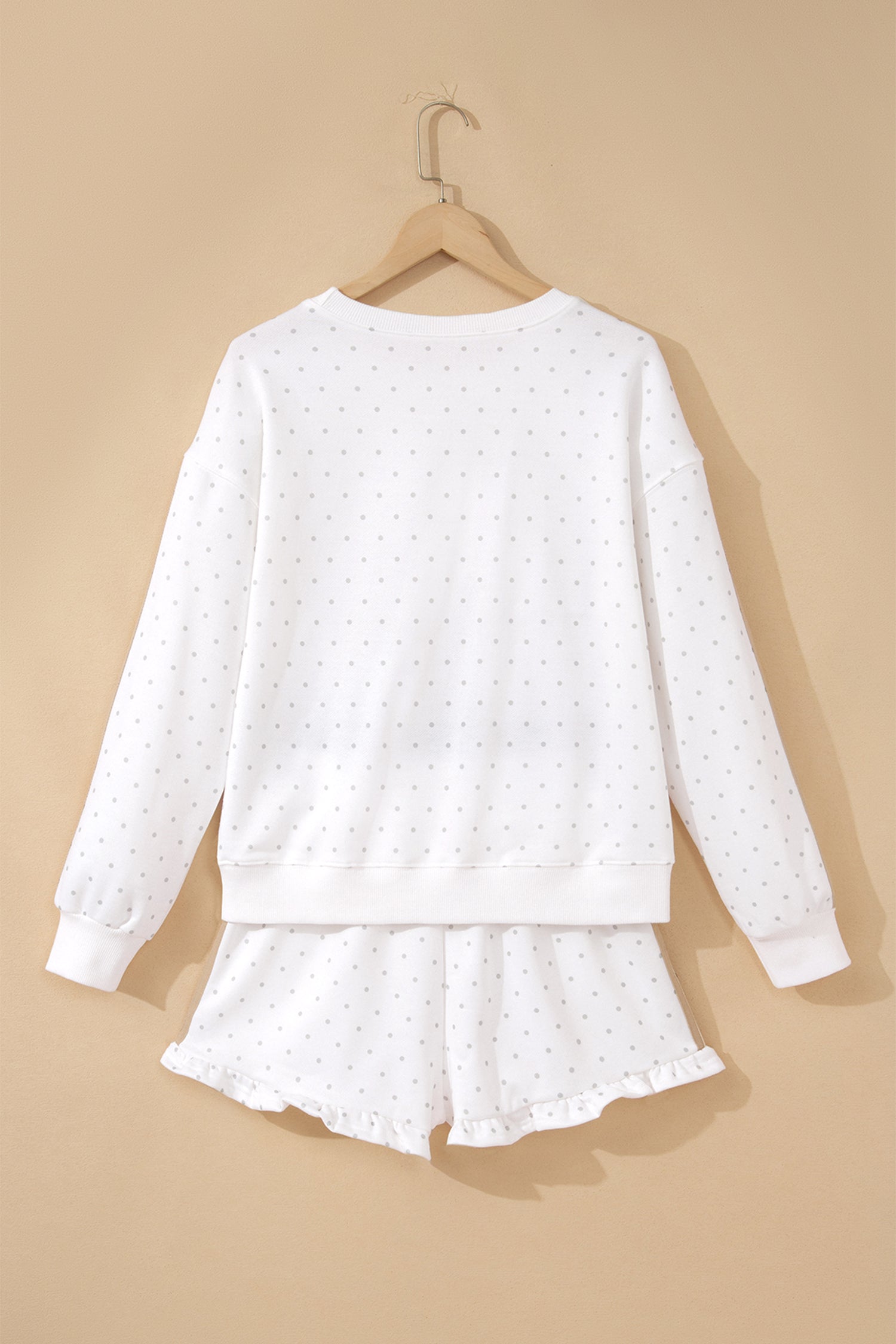 White polka dot sweatshirt and ruffle shorts set on hanger, back view