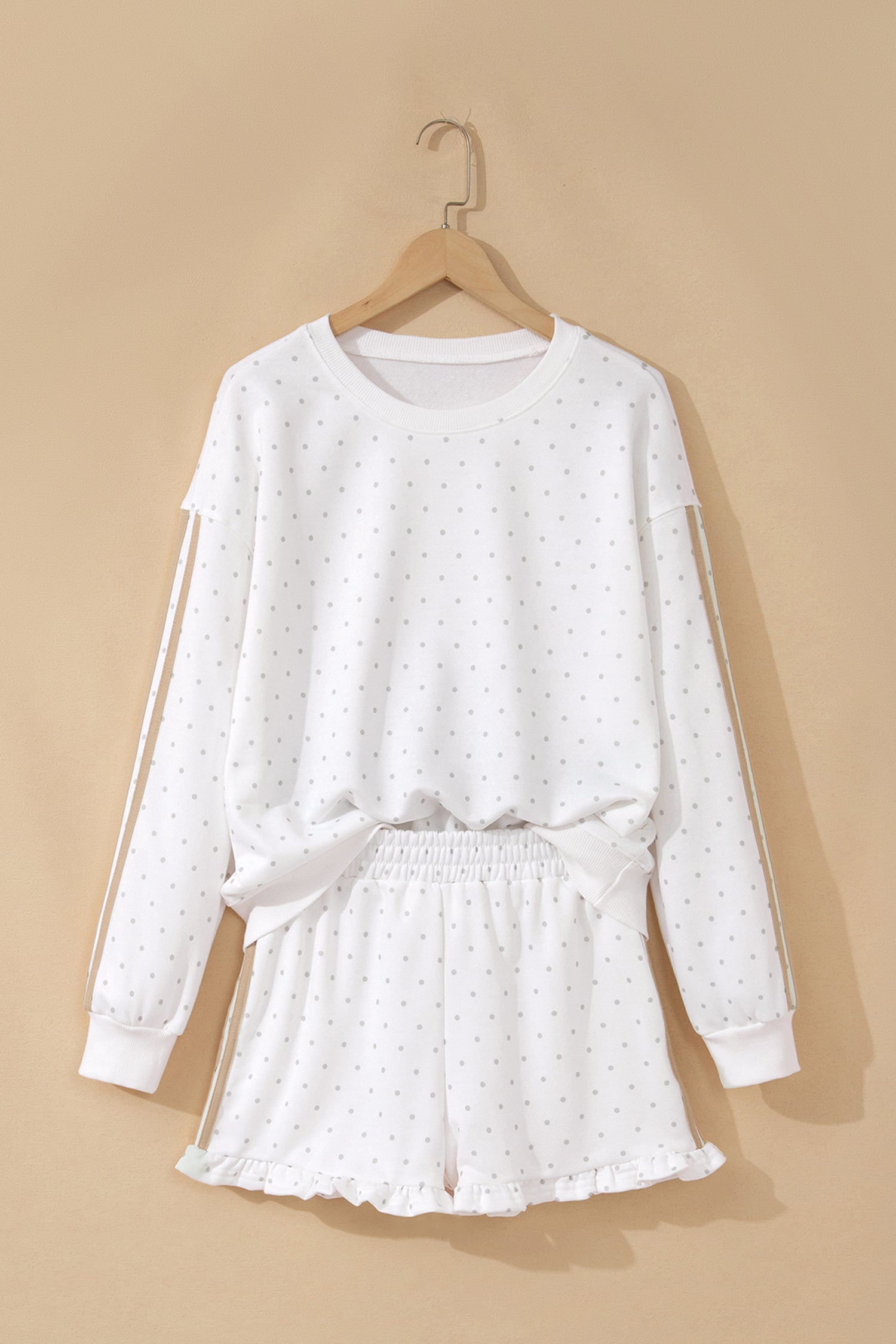 White polka dot sweatshirt and ruffle shorts set on hanger, front view