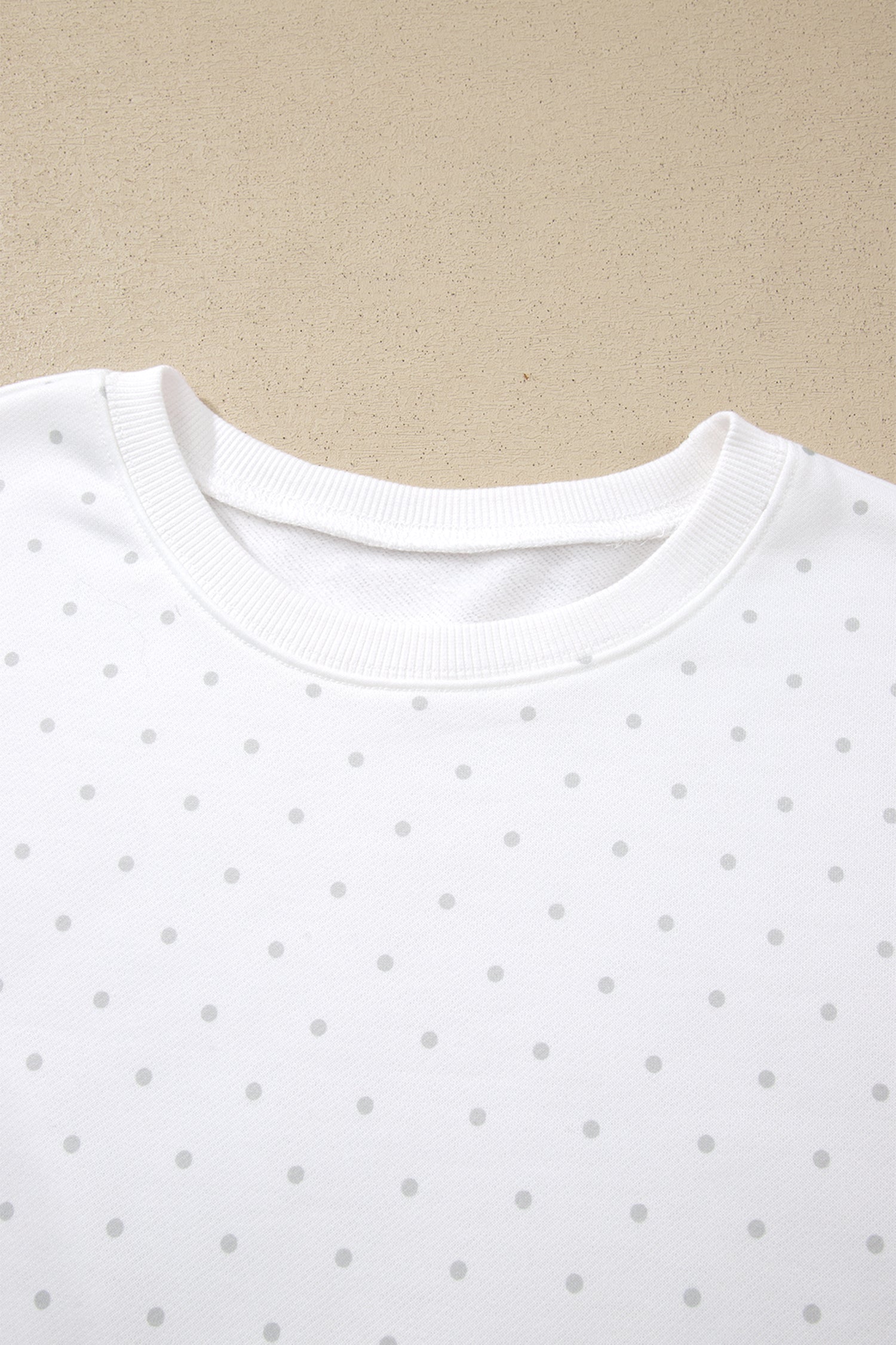 Ribbed round neckline on white polka dot sweatshirt, close-up