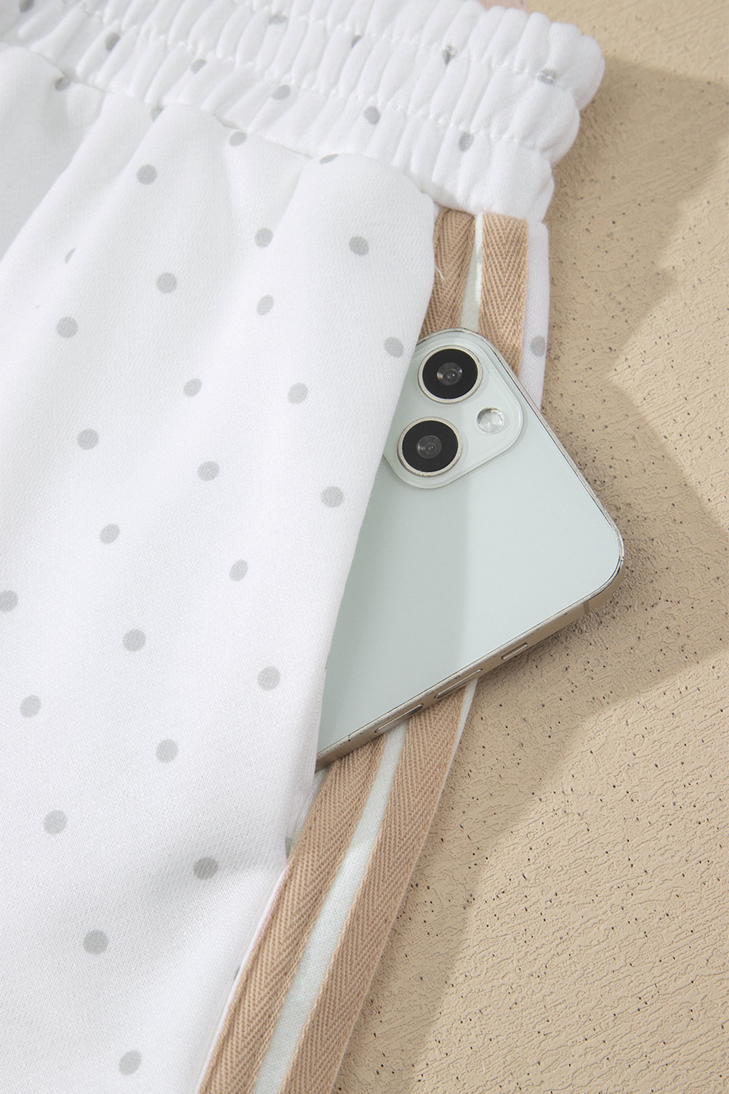 Side pocket holding a phone on white polka dot striped shorts