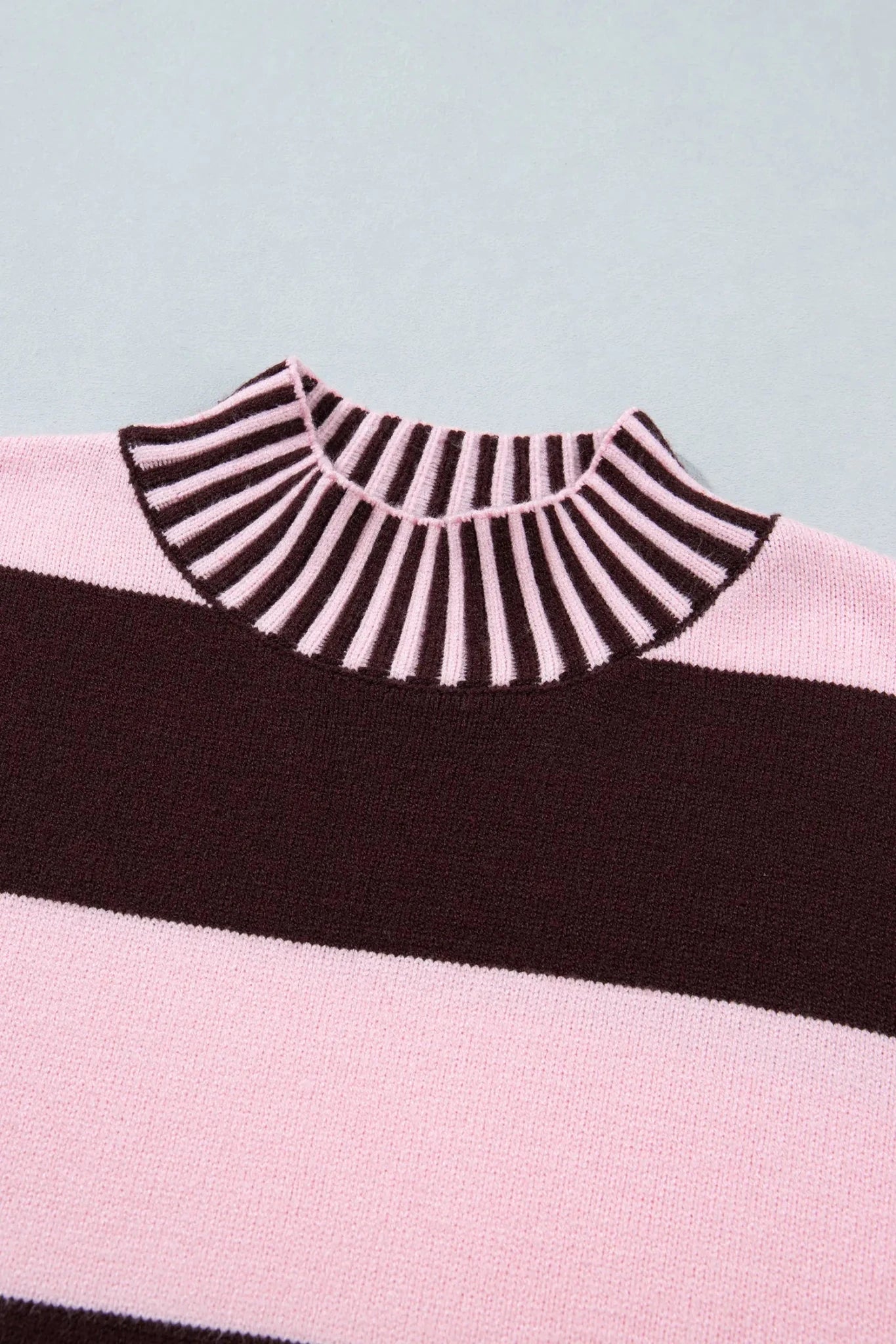 Close-up of knit sweater with dark brown and light pink striped mock neck, wide brown stripe, and pink stripe.