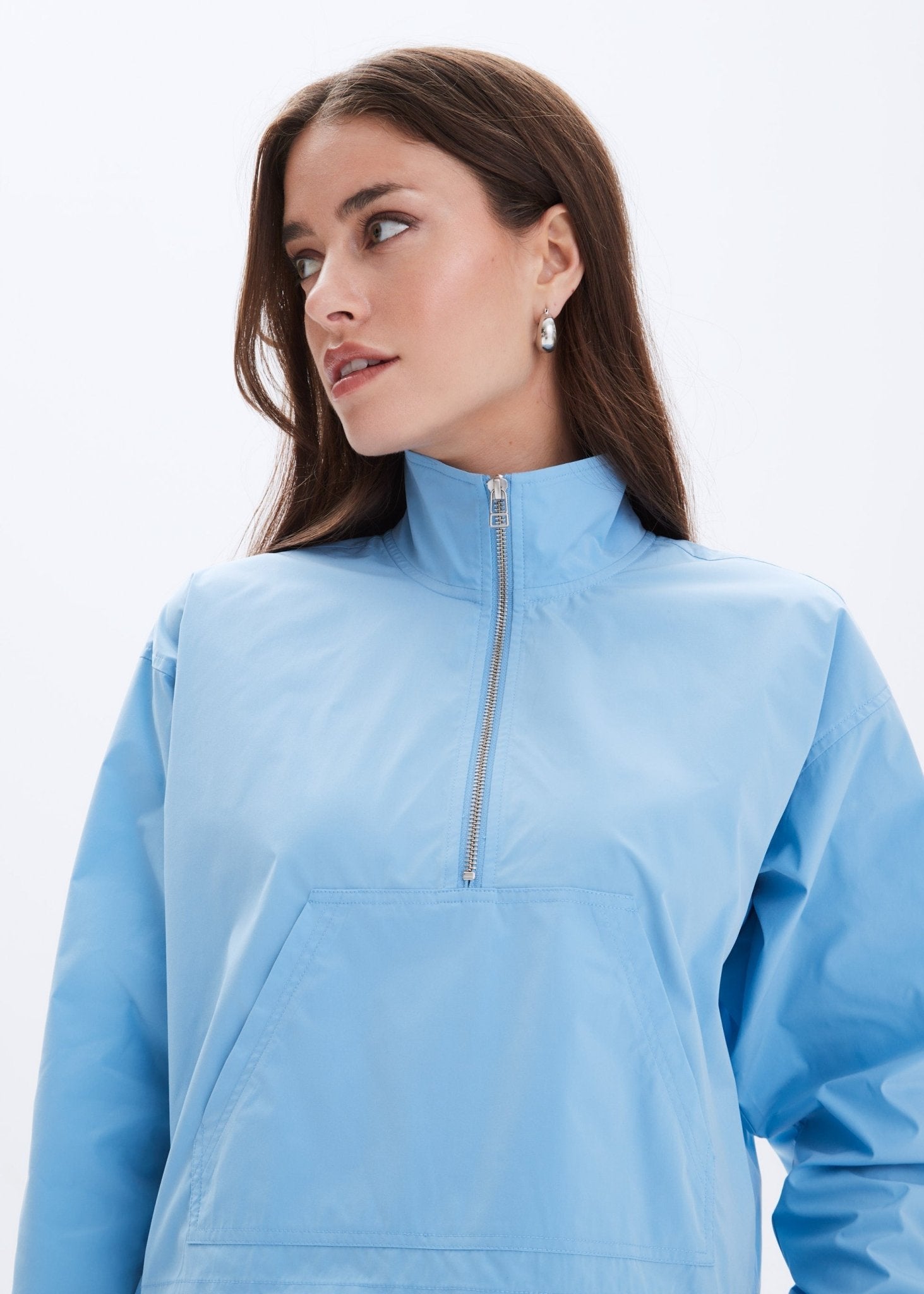 Woman wearing a light blue pullover with a quarter zip on a white background
