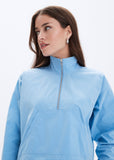 Woman wearing a light blue pullover with a quarter zip on a white background
