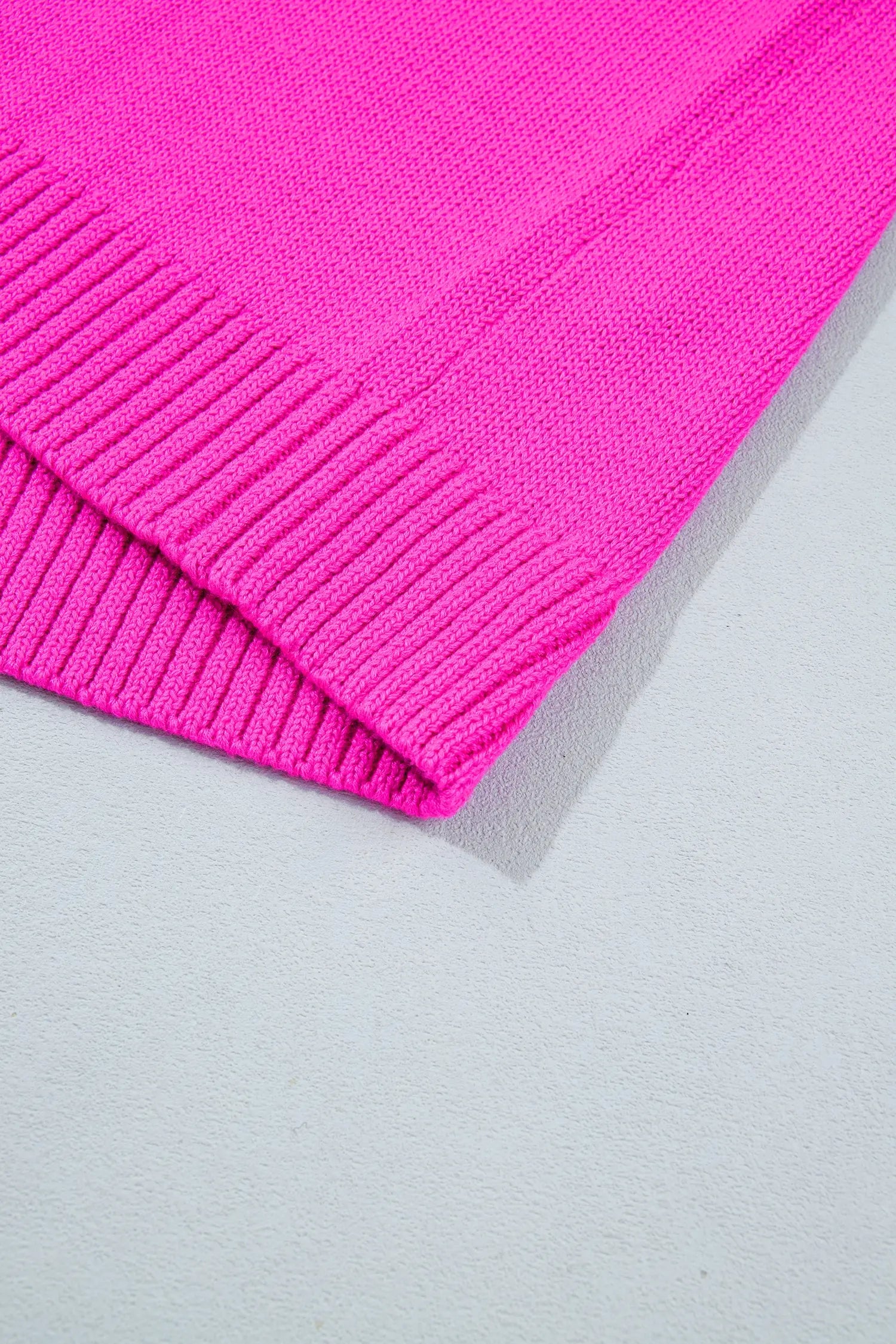Close-up of bright pink ribbed knit fabric with folded hem.