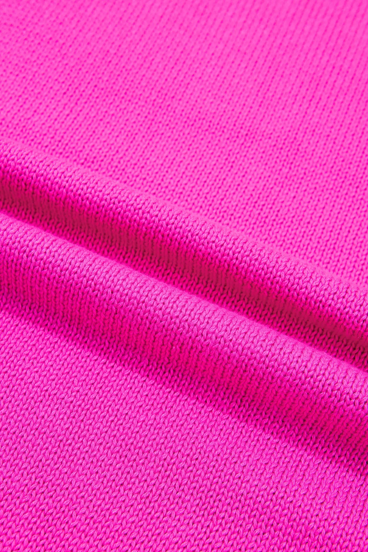 A close-up of bright pink knit fabric with a fine ribbed texture and soft folds.