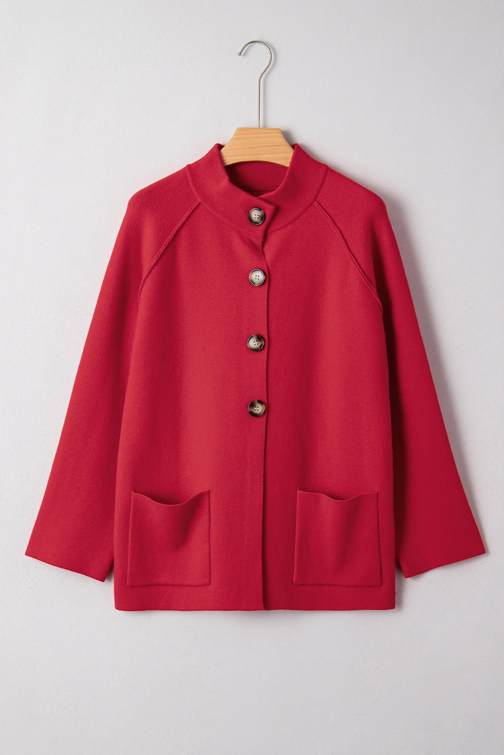 Red coat with button details on a hanger against a white background
