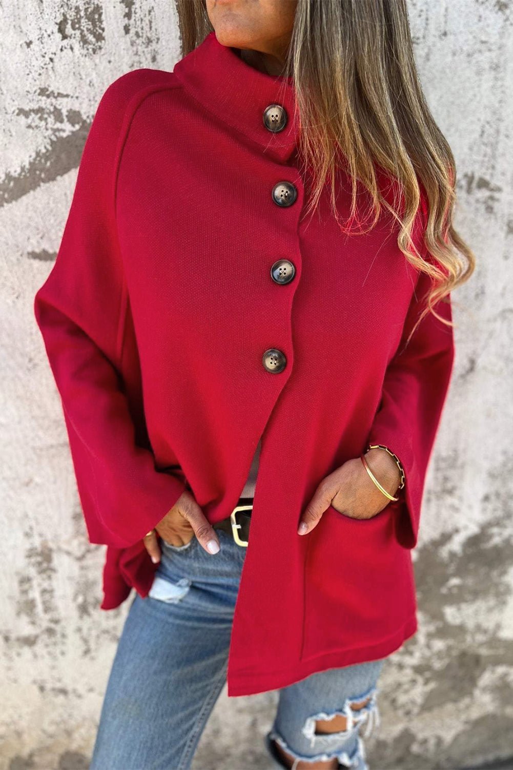 Red coat worn by a person against a textured wall background