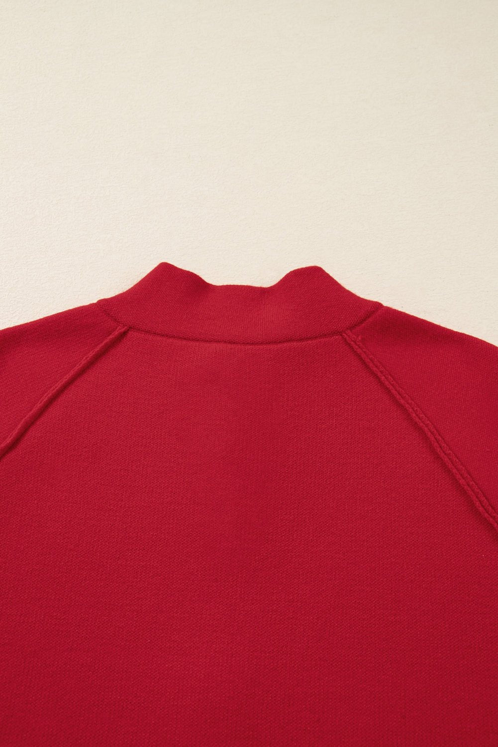 Close-up of a red garment with a collar on a beige background
