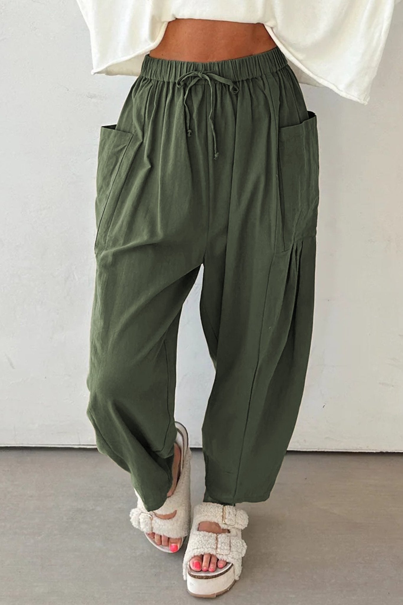 Green wide-leg pants worn with a white top against a plain background