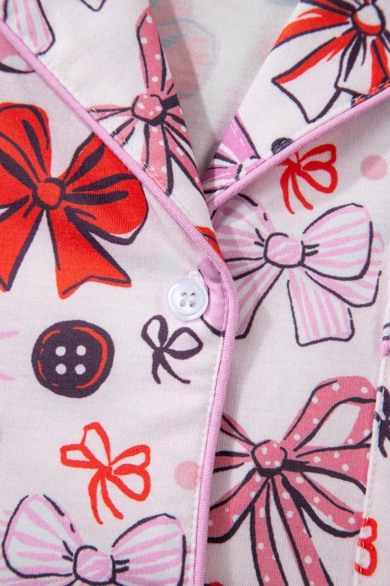 Close-up of a fabric with colorful bow patterns and buttons.