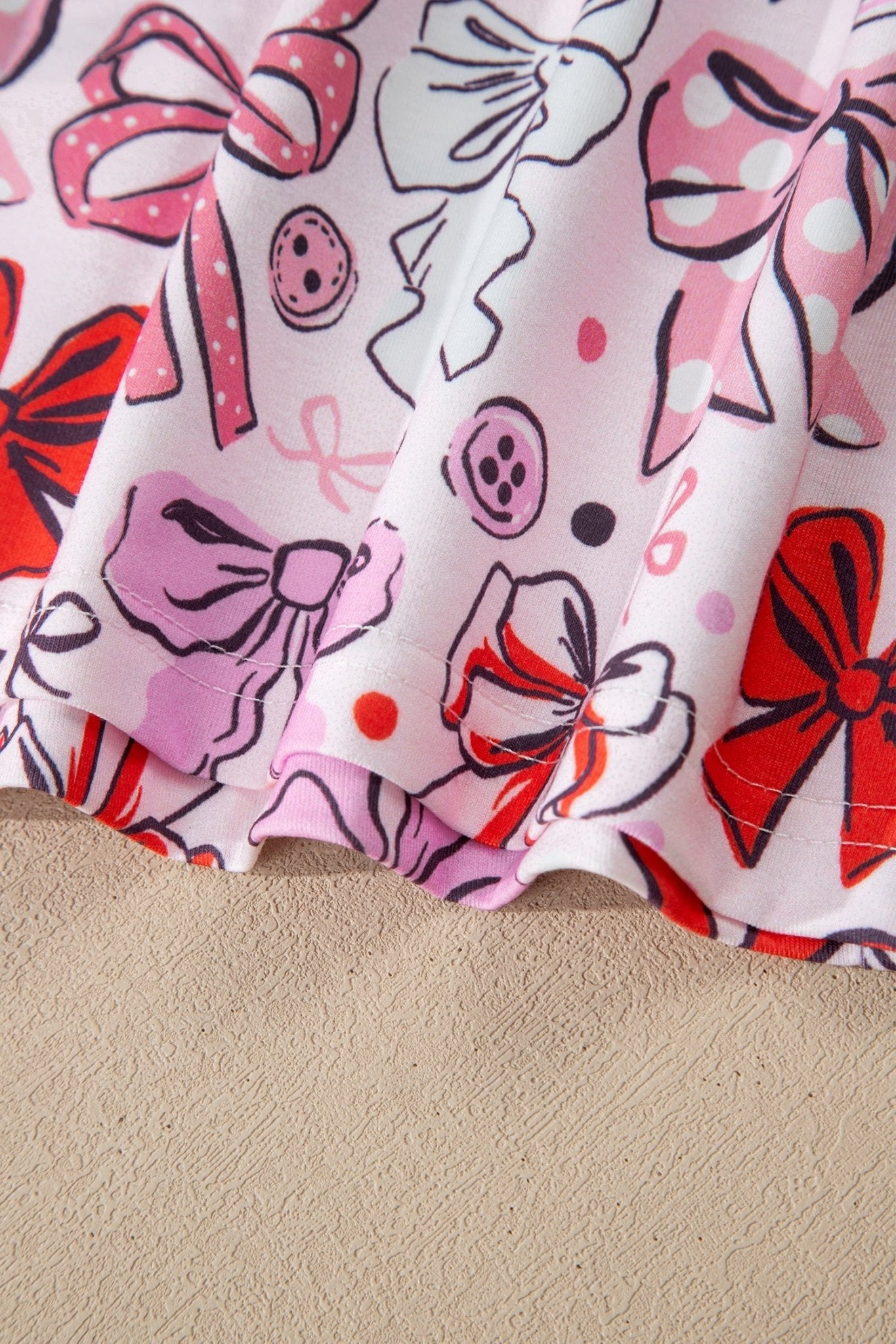 Fabric with colorful bow and button pattern on a beige surface