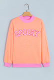 Orange SPOOKY slogan sweatshirt with pink trim on a hanger, front view