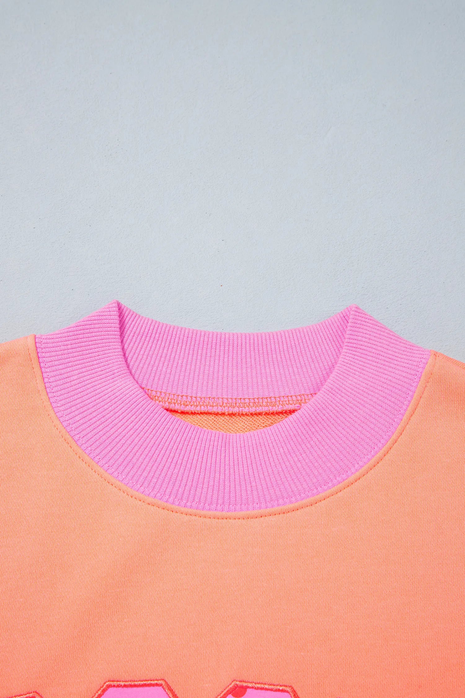 Close-up of orange sweatshirt pink ribbed neckline