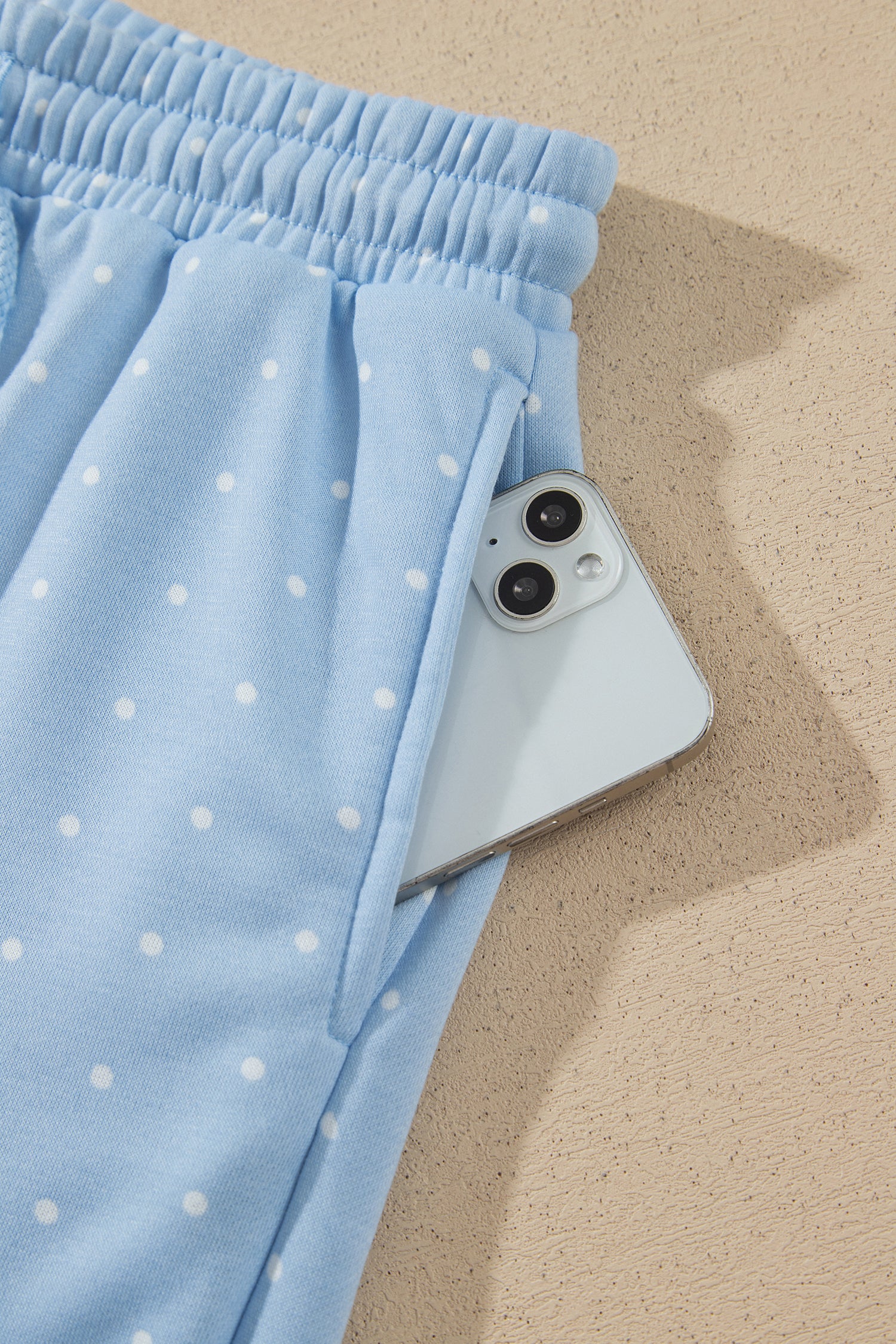 Sky blue polka dot shorts side pocket holding a phone