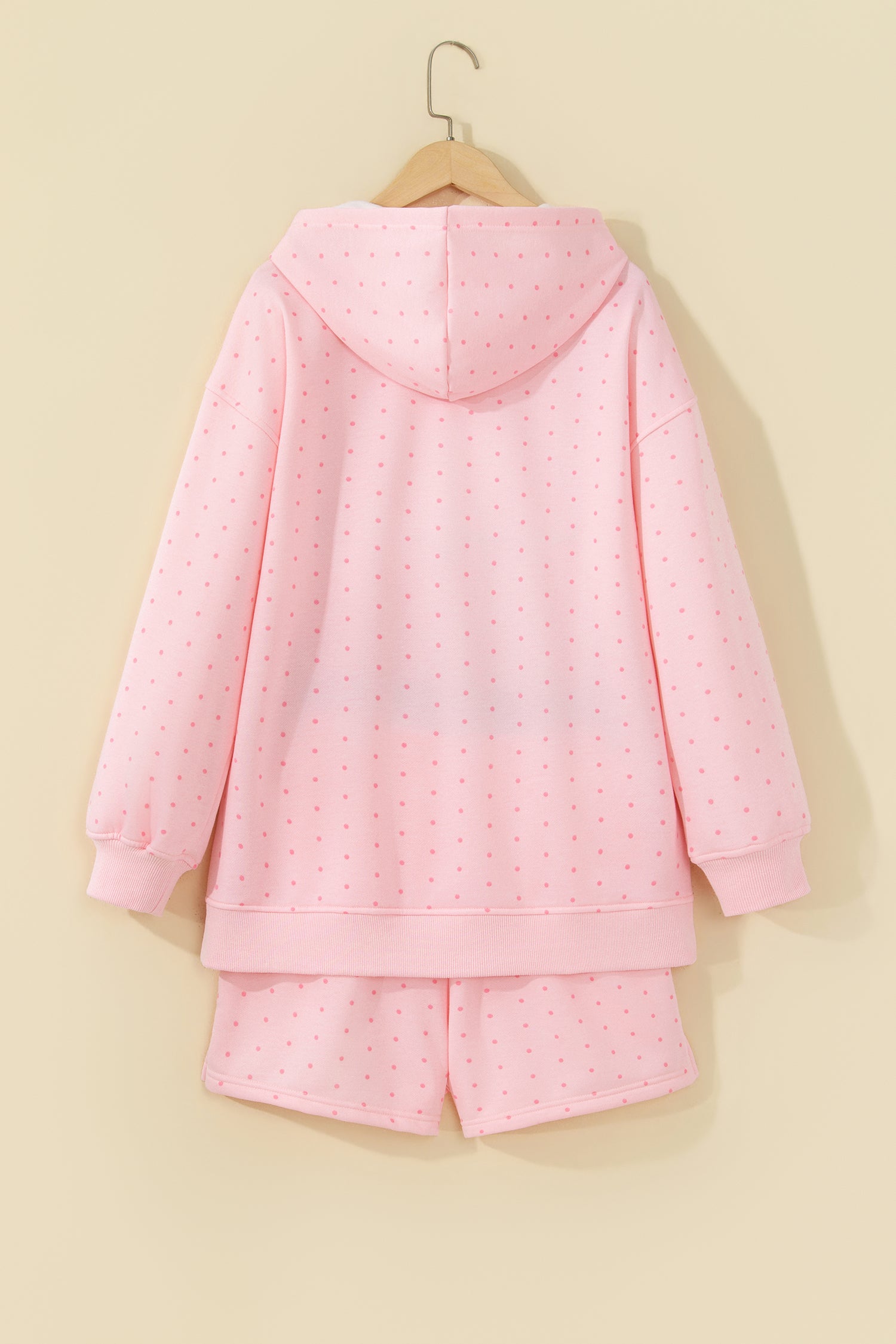 Pink polka dot hoodie and shorts set on a hanger, back view